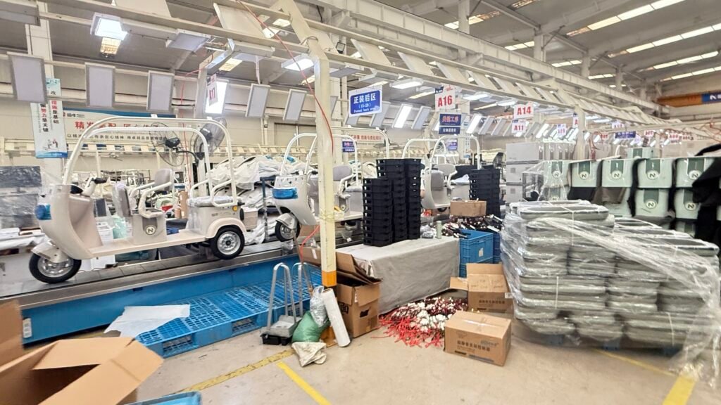 Finished white enclosed electric tricycles undergoing final quality inspection on the assembly line