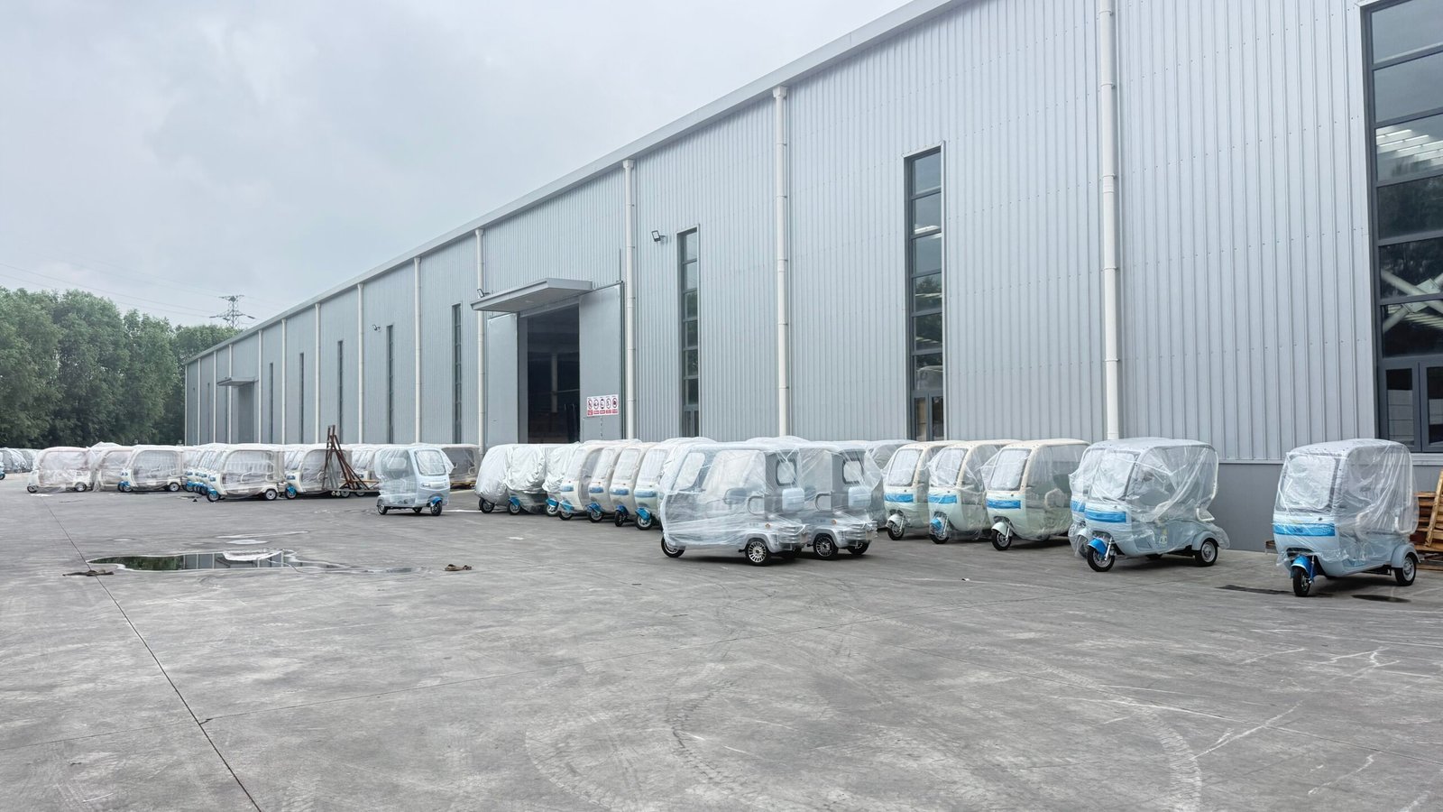 Modern steel-structure electric tricycle factory with packaged units ready for shipment