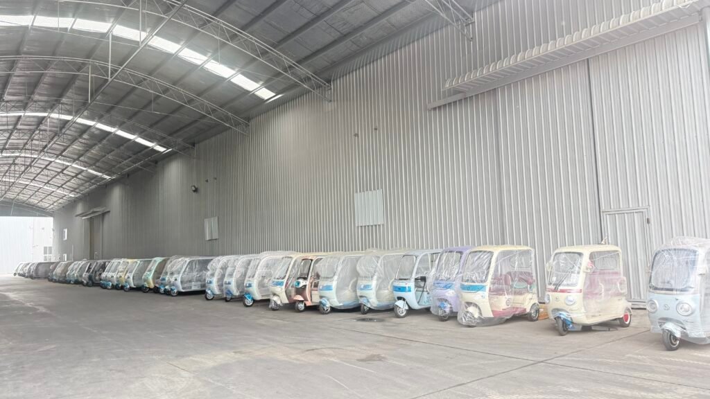 Indoor warehouse with rows of electric tricycles in multiple colors, large ready-stock inventory