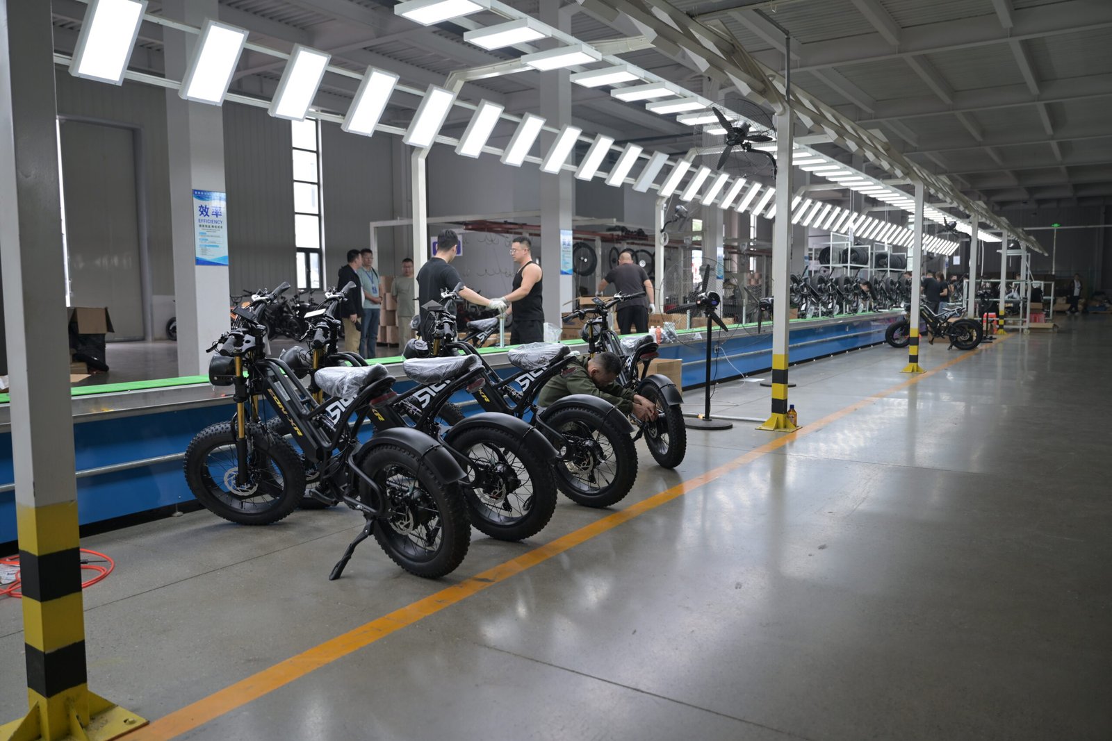 Línea de ensamblaje de vehículos eléctricos en fábrica, trabajadores ensamblando triciclos y motocicletas